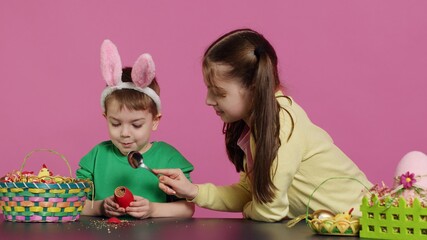 Obraz premium Ecstatic kids breaking a special easter egg to find a surprise inside, feeling curious about a festive decoration that transforms in a plant. Cheerful little children having fun in studio. Camera A.