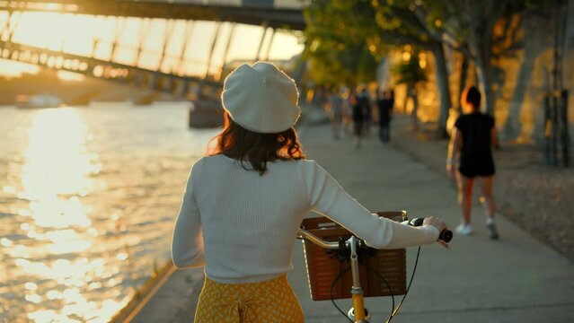 Woman with Bicycle Enjoying Riverside Sunset
