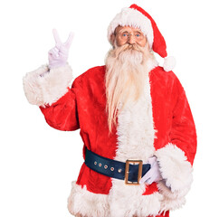 Old senior man with grey hair and long beard wearing traditional santa claus costume showing and pointing up with fingers number two while smiling confident and happy.
