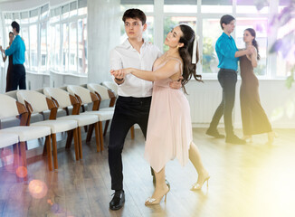 Couples in evening dresses suits enjoys pair dance tango, positively interacting with each other on...