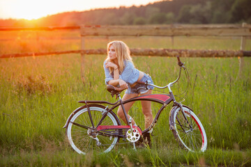 woman relaxing spending time in the countryside on a bicycle at sunset - 780928597