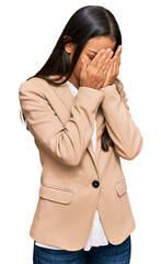Beautiful hispanic woman wearing business jacket with sad expression covering face with hands while...