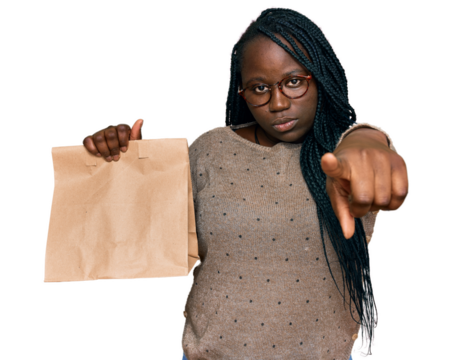 Young black woman with braids holding take away paper bag pointing with finger to the camera and to you, confident gesture looking serious