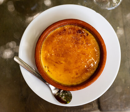 Delicate crema catalana with crisp caramel crust in clay bowl. Traditional Spanish custard dessert ..