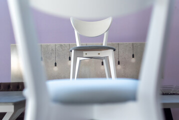 Cabinet furniture. Comfortable white chair framed by another chair close-up in kitchen interior