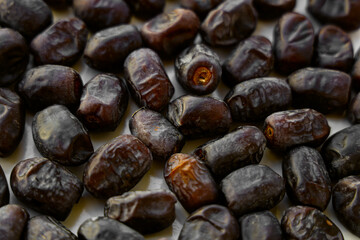 Heap of dried dates on white food background from top view. An abstract pattern of irregularly stacked brown dates