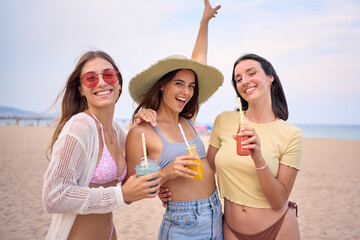 Excited group generation z European women together posing on beach embracing looking smiling at...