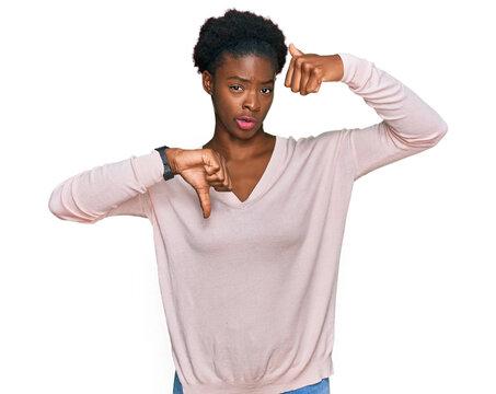 Young african american girl wearing casual clothes doing thumbs up and down, disagreement and agreement expression. crazy conflict