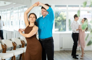 Young man and young woman dance ballroom dance waltz in studio