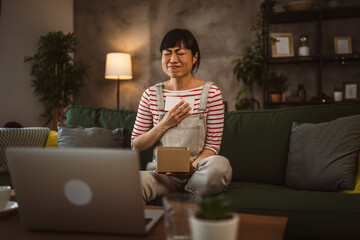 one mature woman open box presents and read card while on video call