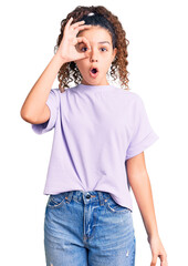 Beautiful kid girl with curly hair wearing casual clothes doing ok gesture shocked with surprised face, eye looking through fingers. unbelieving expression.