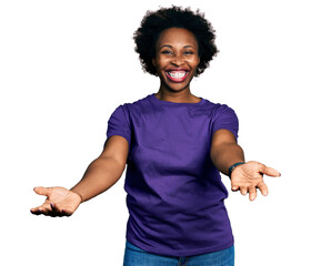 African american woman with afro hair wearing casual purple t shirt smiling cheerful offering hands...