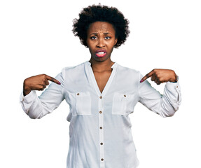 African american woman with afro hair pointing with fingers to herself clueless and confused...