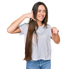 Young hispanic girl wearing casual white t shirt smiling doing talking on the telephone gesture and...