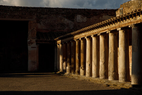 Ancient Roman colonnade, columns bathed in the golden hues of sunset. Pompeii, Italy.
