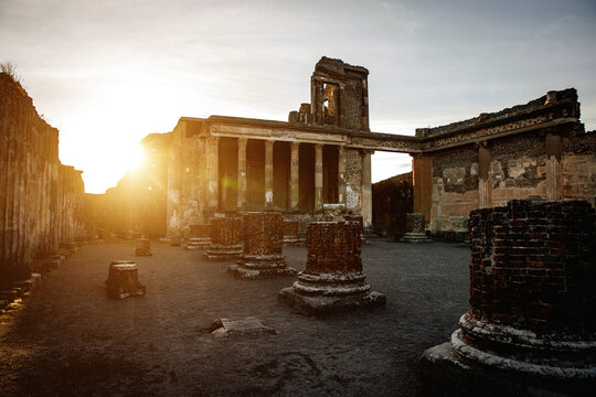 An ancient, partially ruined temple stands bathed in the golden hue of a setting sun.