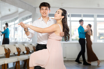 Enthusiastic young couple, elegant Latin American guy and dark-haired girl in formal wear,...