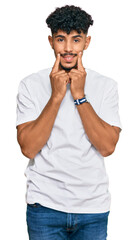 Young arab man wearing casual white t shirt smiling with open mouth, fingers pointing and forcing cheerful smile