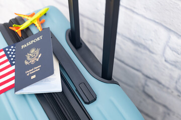 A US passport sits on a suitcase next to a US flag and a toy airplane.