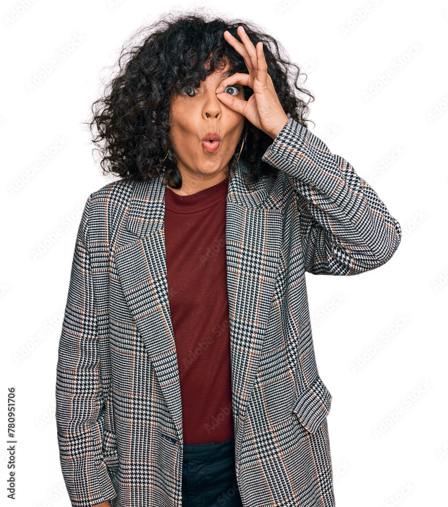 Poster Young hispanic woman wearing business clothes doing ok gesture shocked with surprised face, eye looking through fingers. unbelieving expression.