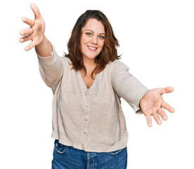 Young plus size woman wearing casual clothes looking at the camera smiling with open arms for hug. cheerful expression embracing happiness.