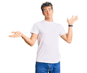 Young handsome man wearing casual white tshirt clueless and confused expression with arms and hands raised. doubt concept.