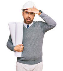 Handsome middle age man holding paper blueprints stressed and frustrated with hand on head,...