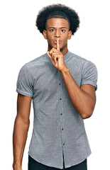 African american man with afro hair wearing casual clothes asking to be quiet with finger on lips....