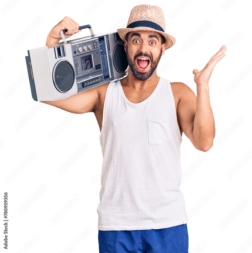 Canvas Prints Young hispanic man holding boombox, listening to music celebrating victory with happy smile and winner expression with raised hands