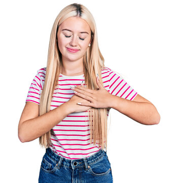Beautiful blonde woman wearing casual striped t shirt smiling with hands on chest with closed eyes and grateful gesture on face. health concept.