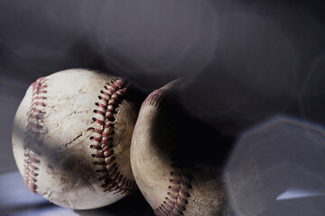 Old used baseball balls with light over black sports background, nostalgia image.
