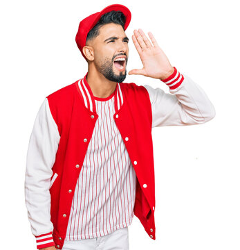 Young man with beard wearing baseball uniform shouting and screaming loud to side with hand on mouth. communication concept.