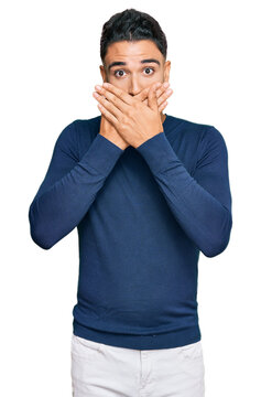 Young man with beard wearing casual blue winter sweater shocked covering mouth with hands for mistake. secret concept.