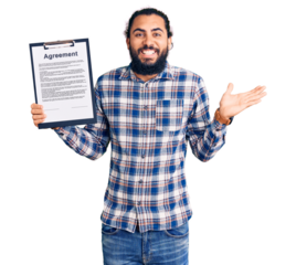 Young arab man holding clipboard with agreement document celebrating victory with happy smile and winner expression with raised hands