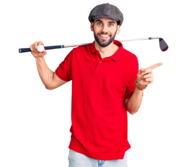 Young handsome man with beard playing golf holding club and ball smiling happy pointing with hand and finger to the side