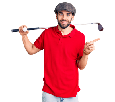 Young handsome man with beard playing golf holding club and ball smiling happy pointing with hand and finger to the side