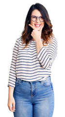 Obraz premium Beautiful young brunette woman wearing casual clothes and glasses looking confident at the camera smiling with crossed arms and hand raised on chin. thinking positive.