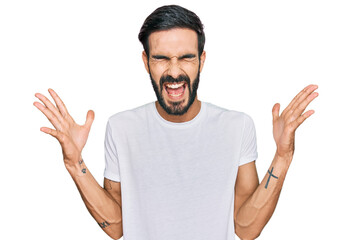 Young hispanic man wearing casual white t shirt celebrating mad and crazy for success with arms...
