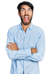 Fototapeta premium Hispanic man with blue eyes with arms crossed gesture angry and mad screaming frustrated and furious, shouting with anger looking up.