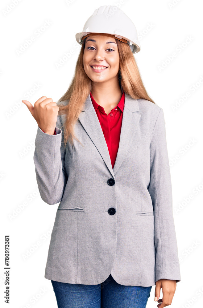 Poster beautiful young woman wearing architect hardhat smiling with happy face looking and pointing to the 