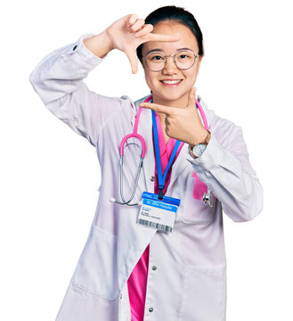 Young chinese woman wearing doctor uniform and stethoscope smiling making frame with hands and fingers with happy face. creativity and photography concept.