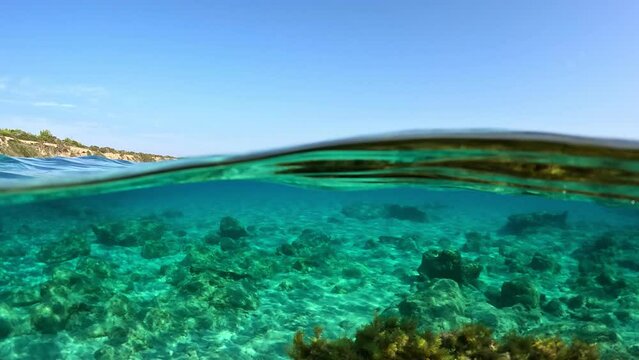 Half underwater slow motion shot of clear turquoise water. Crystal clear blue water in Mediterranean Sea on the coast of Cyprus. High quality slow motion UHD