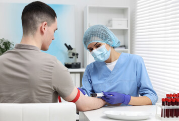 Obraz premium Laboratory testing. Doctor taking blood sample from patient at white table in hospital