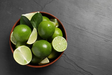 Fresh ripe limes in bowl on black table, top view. Space for text