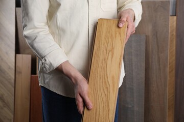 Man with sample of wooden flooring indoors, closeup