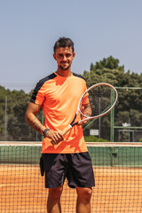 Man in sportswear playing tennis on a dirt tennis court