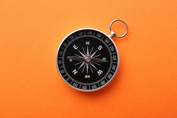 One compass on orange background, top view. Tourist equipment © New Africa