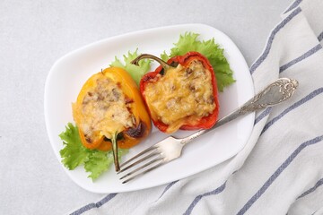 Delicious stuffed peppers and fork on light table, top view