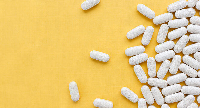 Dietary supplement with vitamin C and citrus bioflavonoid on yellow background. Medical banner. Selective soft focus, copy space
