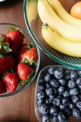 strawberries and blueberries in bowls on a table